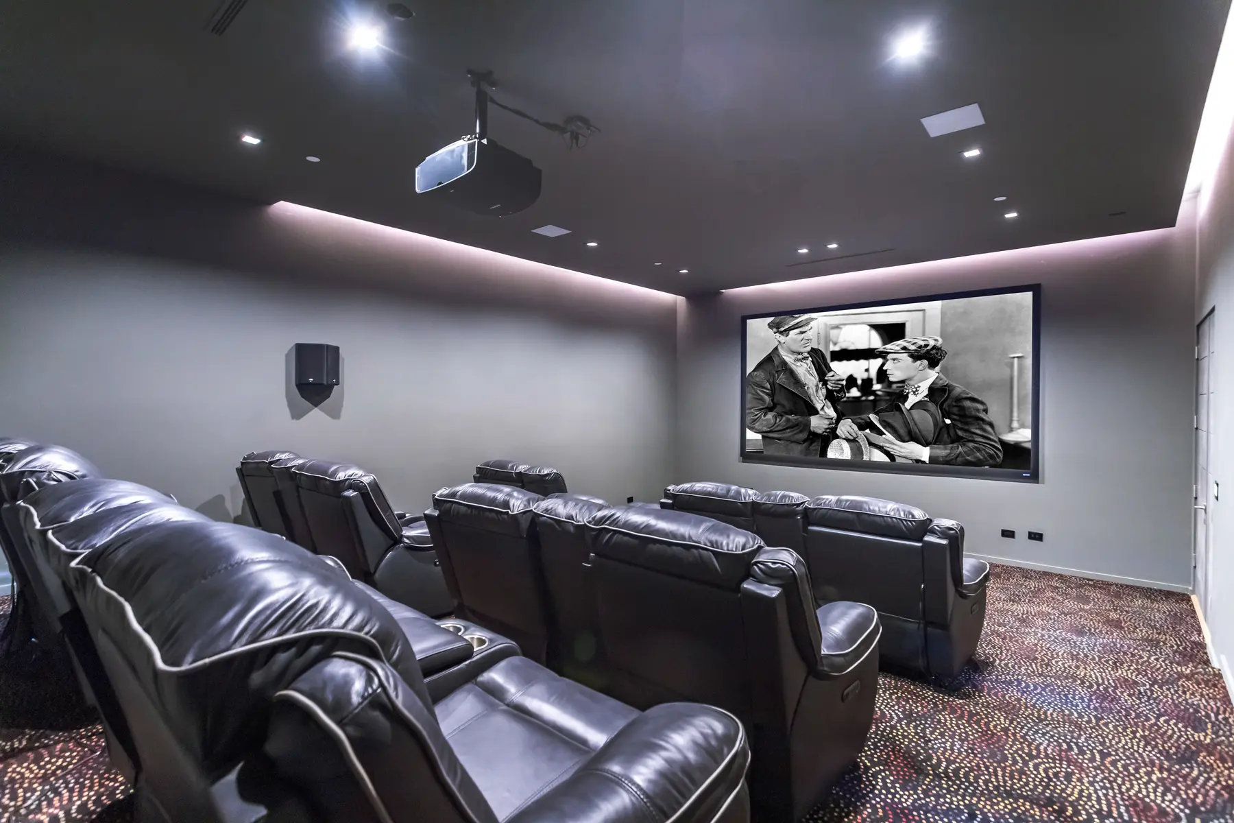 Home theater with rows of reclining seats facing a large screen, an interior by Apel Design