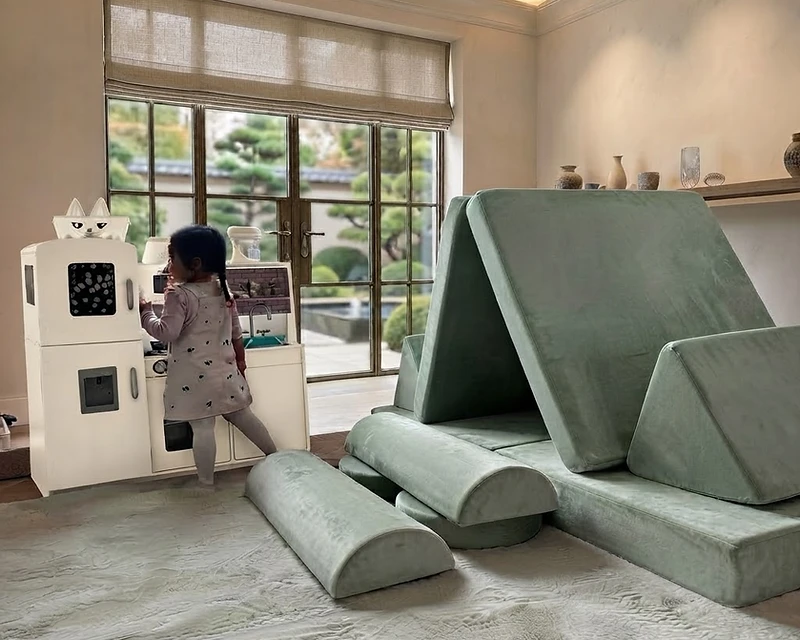 The Nanola modular play couch arranged as a sculptural reading nook in a sun-drenched living room