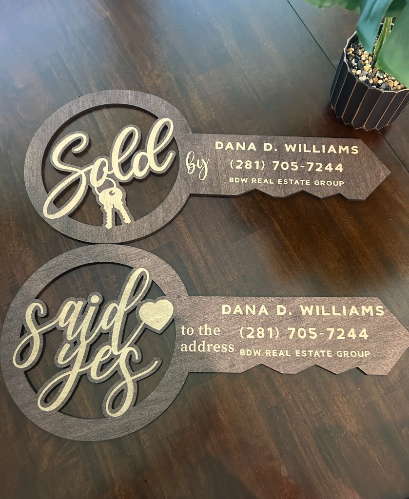 Stained wood key-shaped signs with gold-finished typography on a dark wood table