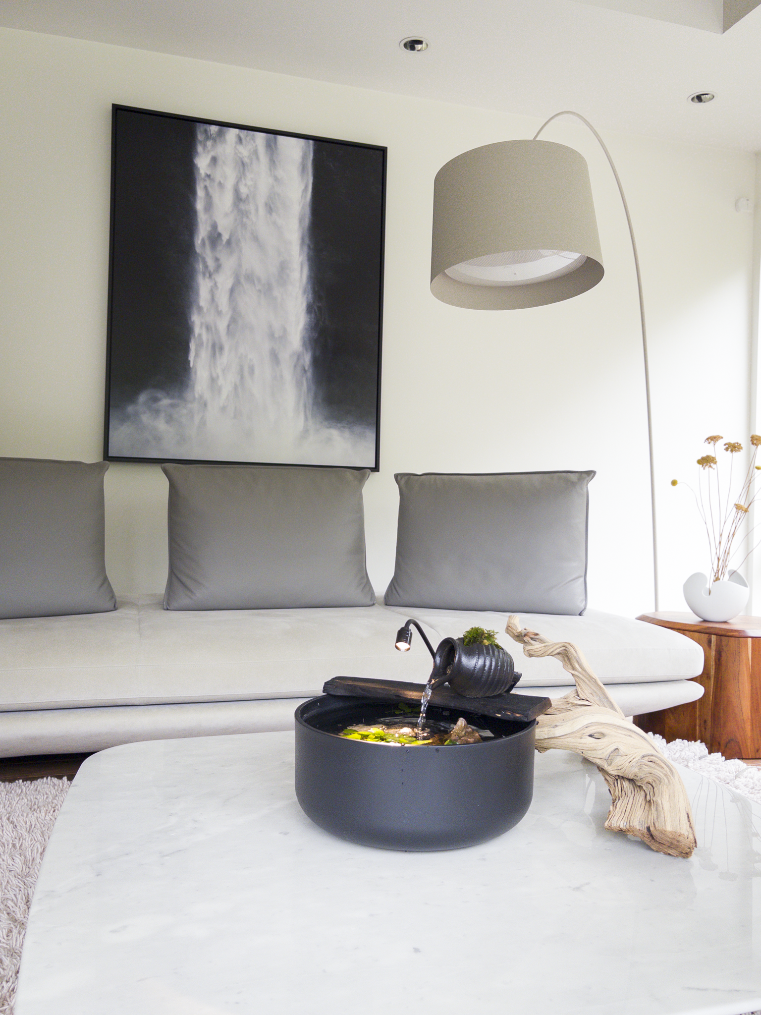 The Sanctuary Vessel on a white marble coffee table before a sofa with a waterfall print