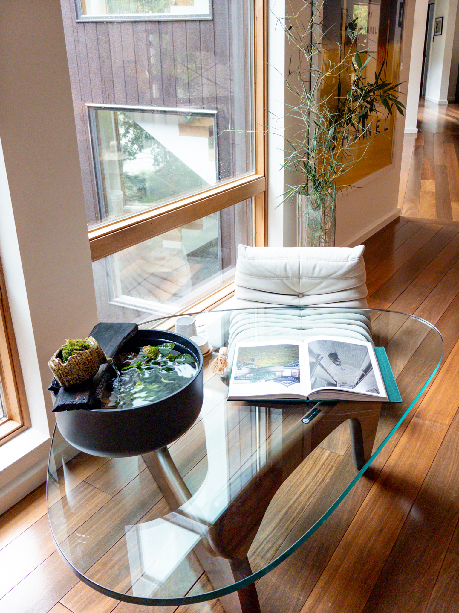 The Sanctuary Vessel resting on a glass coffee table beside a cream floor chair