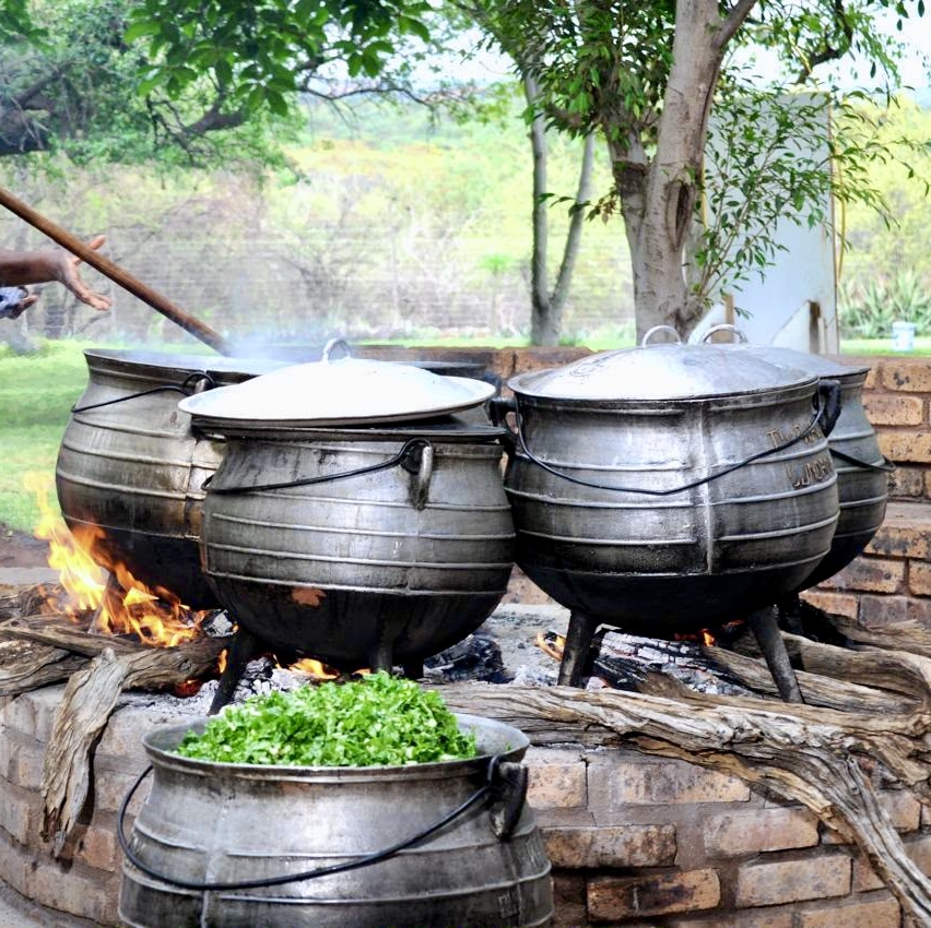 Cast iron potjie pots simmering over an open fire