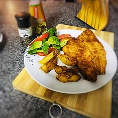 Golden pan-fried fish with roasted wedges and fresh salad — comfort, plated.