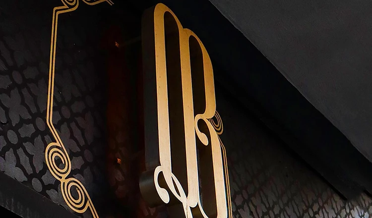Monograma QB en oro — insignia del grupo
