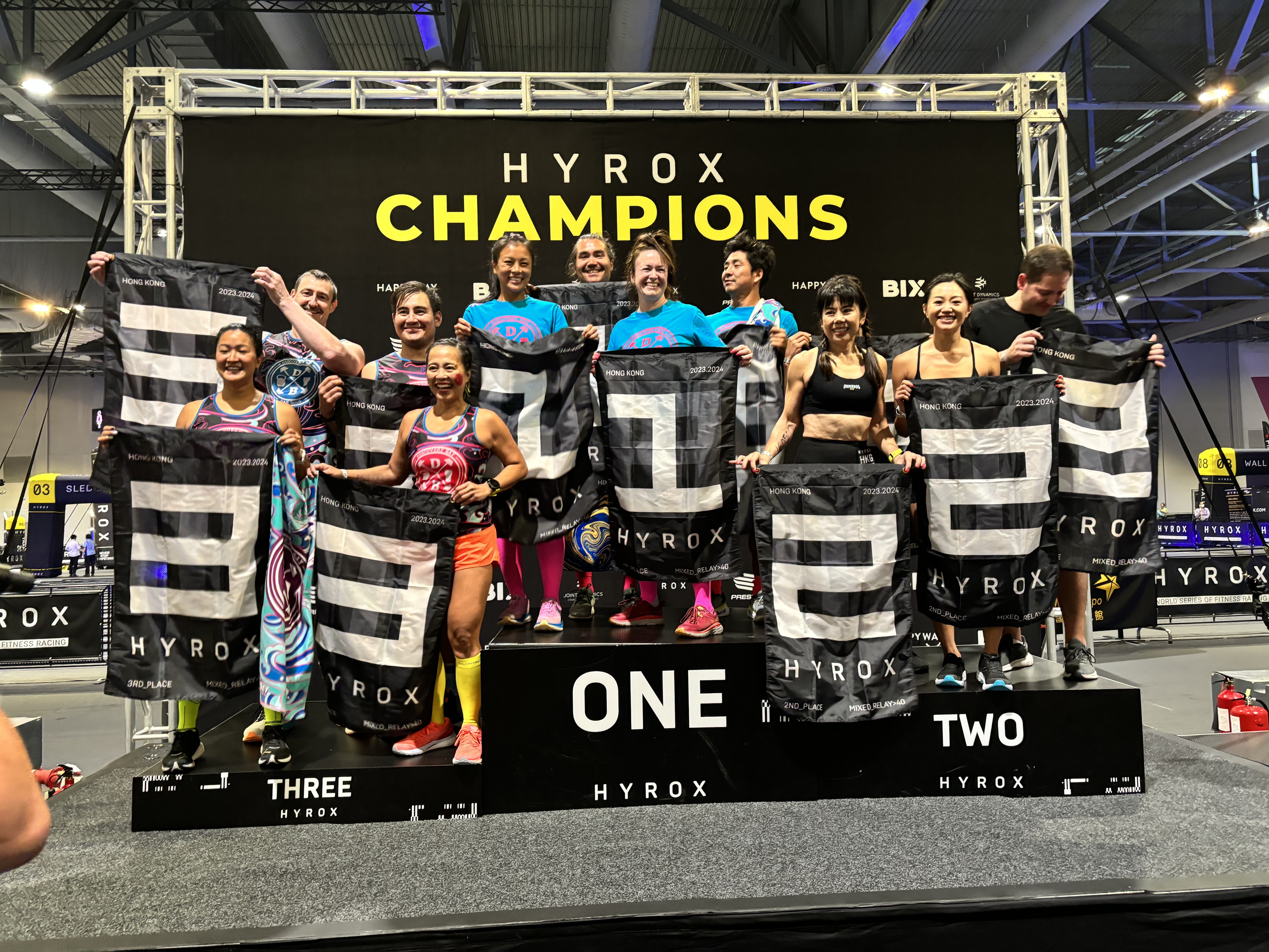 DBDB athletes on the HYROX Hong Kong Relay podium with 3rd-place flags