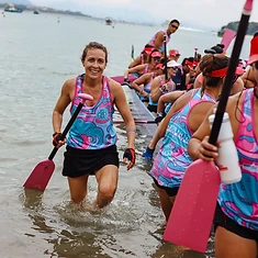 DBDB paddler stepping out of the water with her pink paddle