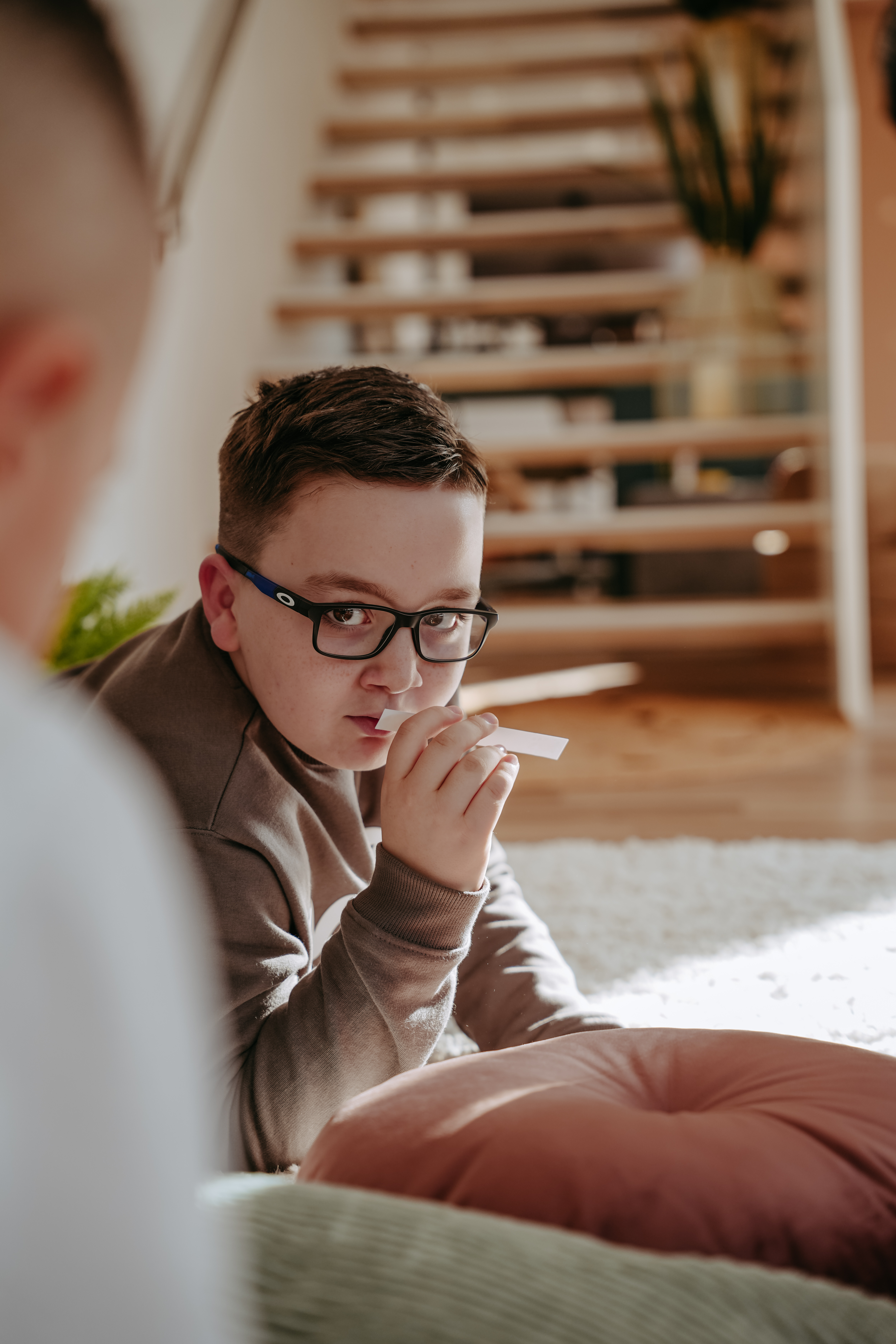 Junge mit Brille auf Teppich