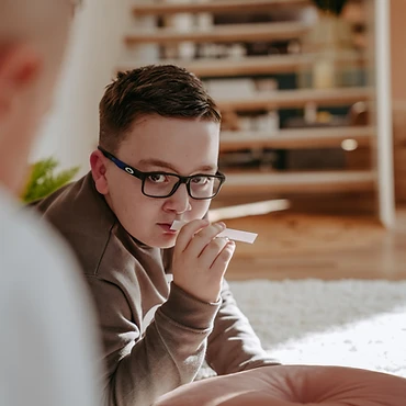 Junge mit Brille auf Teppich