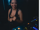Female DJ laughing behind the decks under neon blue and red light