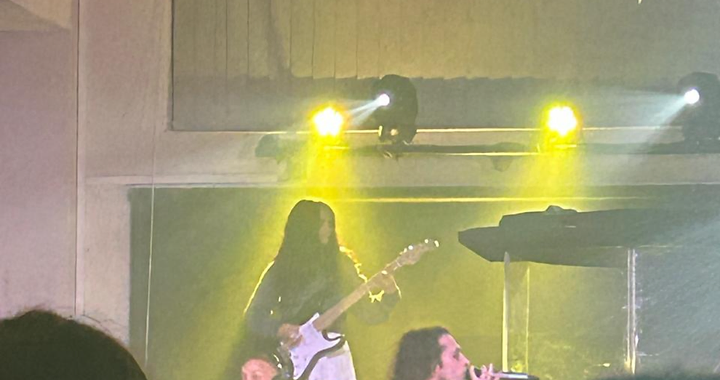 Live acoustic trio performing under warm stage spotlights — keys, bass and vocals