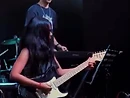 Live musician playing electric guitar on a dim stage with blue and red stage lighting
