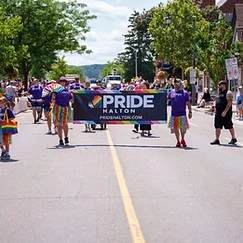 Community members carrying the Pride Halton banner down Main Street Milton during the 2026 parade