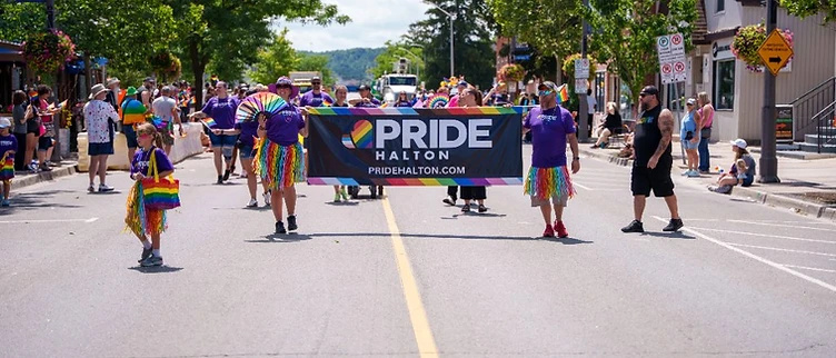 Community members carrying the Pride Halton banner down Main Street Milton during the parade