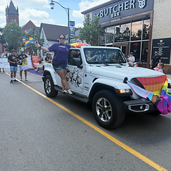 White Jeep Wrangler draped with a Progress Pride flag in the Pride Halton 2026 parade