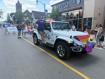 White Jeep Wrangler draped with a Progress Pride flag in the Pride Halton parade