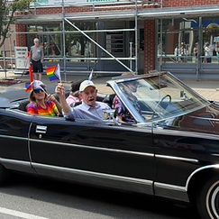 Vintage black convertible carrying parade participants with Progress Pride flags in the Pride Halton 2026 parade