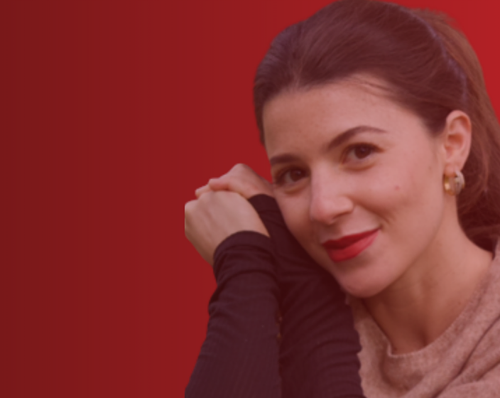Mira smiling against a deep red backdrop