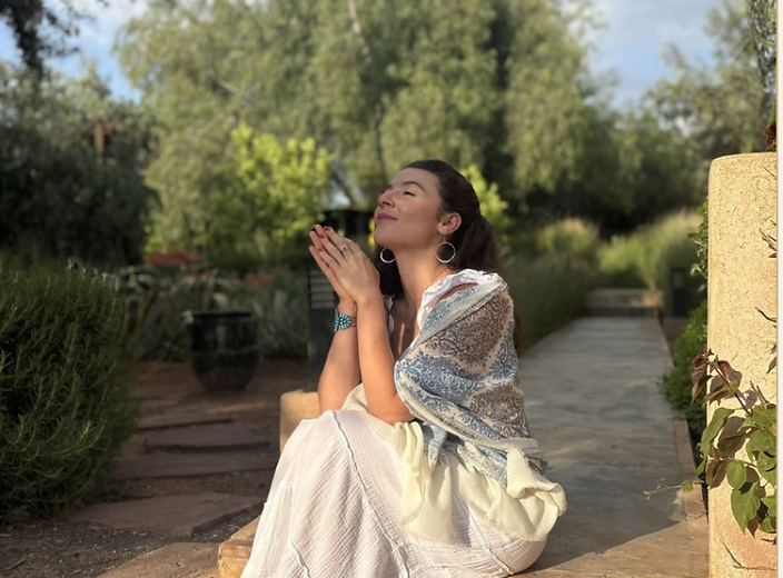 Mira seated on garden steps in a moment of gratitude