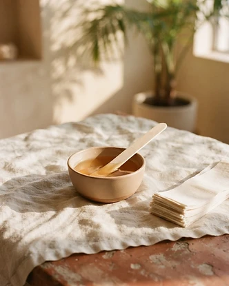 Warm wax and wooden applicator on ivory linen