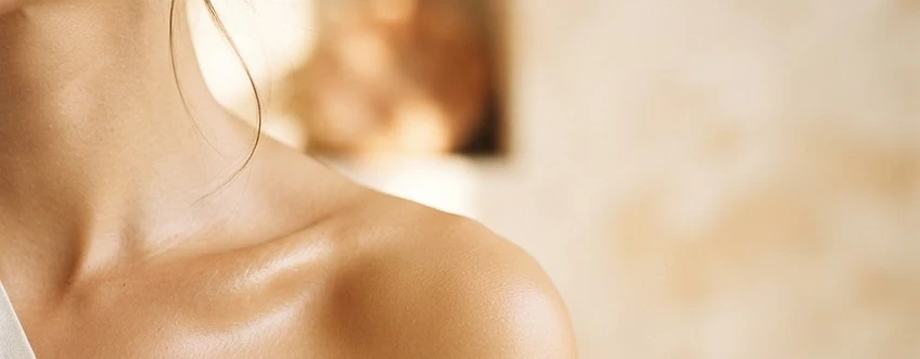 Golden sunlight illuminating a woman's shoulder and delicate necklace