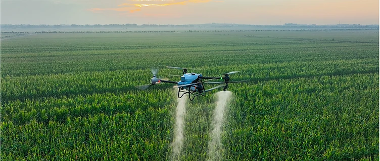 Agricultural spraying drone applying a fine mist over a green field