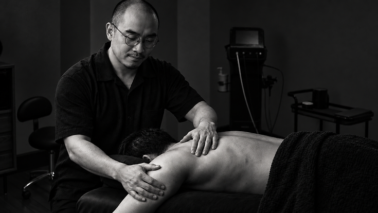 AI-generated black-and-white scene of Gary Ng providing shoulder assessment and bodywork in a setting based on his clinic