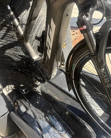 KTM-E-Bike während der Reinigung in der mobilen Fahrradwaschanlage — rotierende Bürsten am Rahmen