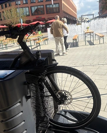 Mobile cycleWASH Fahrradwaschanlage auf einem Stadtplatz mit Brunnen im Hintergrund