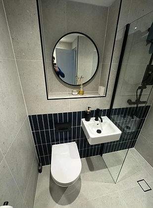 Modern bathroom with wall-mounted basin and navy blue feature tiles
