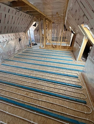 White underfloor heating pipe looped in a serpentine pattern across insulated battens