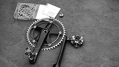 Cycliste inspectant une cassette, un dérailleur et d’autres composantes de vélo d’occasion sur un établi 