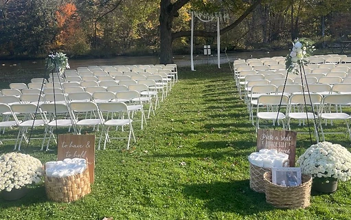 White folding chairs lined up for an outdoor wedding ceremony aisle