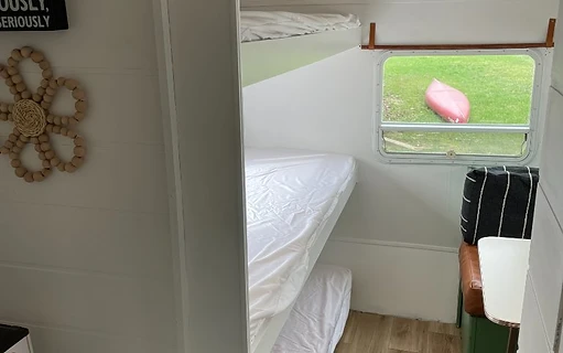 Camper bunk bed area with booth seating and window view