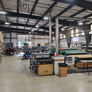 Wide view of the screen printing facility with carousel press, conveyor dryer, and apparel staging