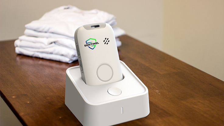 A Sentinel Pulse charging in its dock on a bedroom dresser