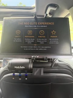 Headrest screen showing The NEO Elite Experience, with phone charging cables ready