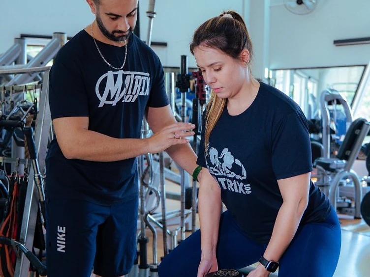 Personal trainer orientando aluno na sala de musculação da Academia Matrix 901
