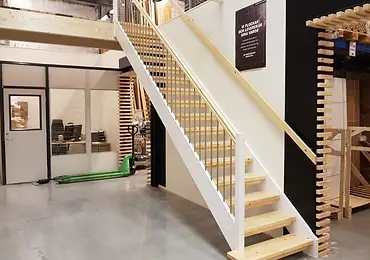 Trappa med vita vangstycken, eksteg och metallbalustrar i industriell miljö