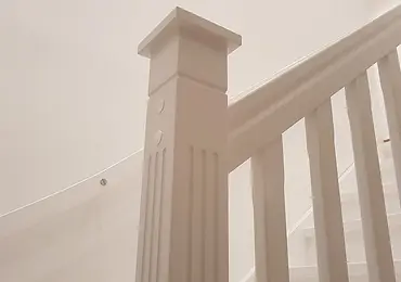 Vitmålad nyckelpelare med räcke, balustrar och dekorativt spår