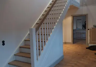 Rak vitmålad trappa med eksteg, träräcke och vita balustrar