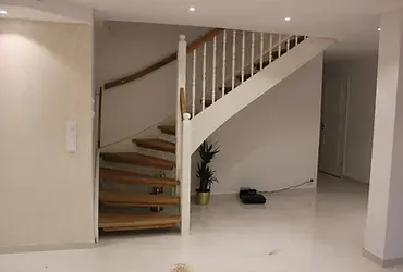 Svängd trappa med eksteg, vita balustrar och träräcke
