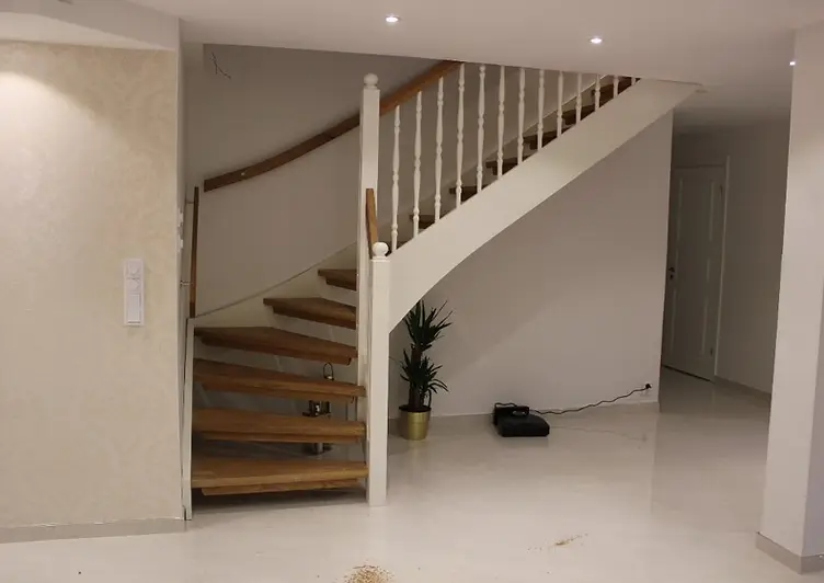Svängd trappa med eksteg, vita balustrar och träräcke