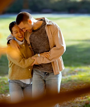 A happy couple laughing together in a sunny park