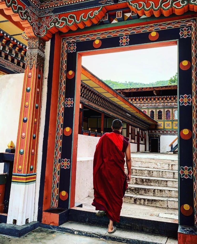 A monk walking through an ornately painted Bhutanese doorway