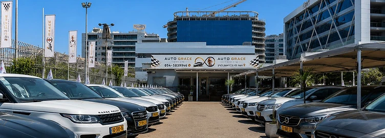 חזית מגרש המכירה של אוטו גרייס בראשון לציון — שתי שורות רכבים מובילות אל מבנה הסוכנות והשלט