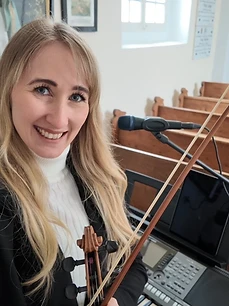 Julia lächelnd mit Geigenbogen in der Kirche
