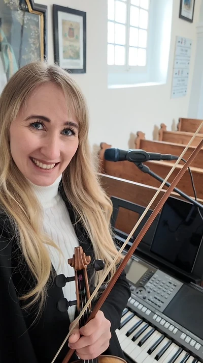 Julia lächelnd mit Geigenbogen in der Kirche