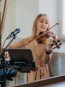 Julia spielt Geige in einem beigefarbenen Kleid in der Kirche