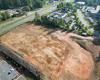 Aerial view of 1018 Sullivan Road in Newnan, Georgia, showing a cleared commercial land site along Sullivan Road with mature tree buffer and adjacent retail.