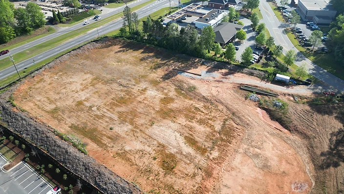 Aerial view of 1018 Sullivan Road in Newnan, Georgia, showing a cleared commercial land site along Sullivan Road with mature tree buffer and adjacent retail.